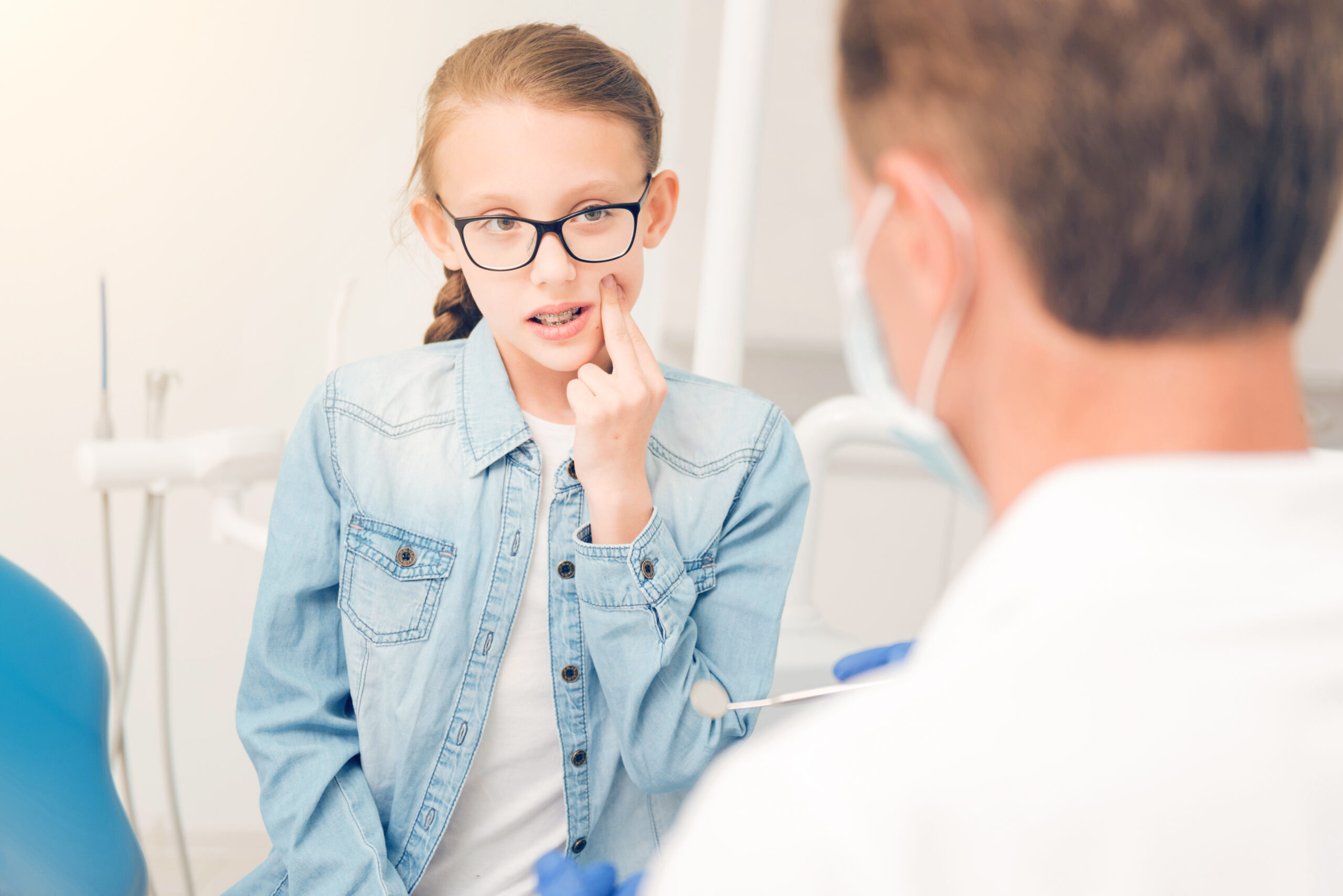 It hurts so much. Waist up shot of a frustrated schoolgirl pressing her cheek with two fingers while struggling with a horrible toothache and visiting a dentist for treating her teeth.