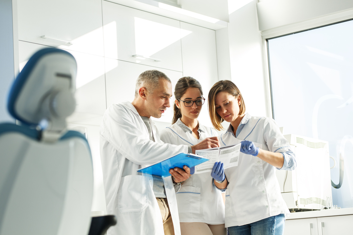Dentists team in dental office examining list of patients.