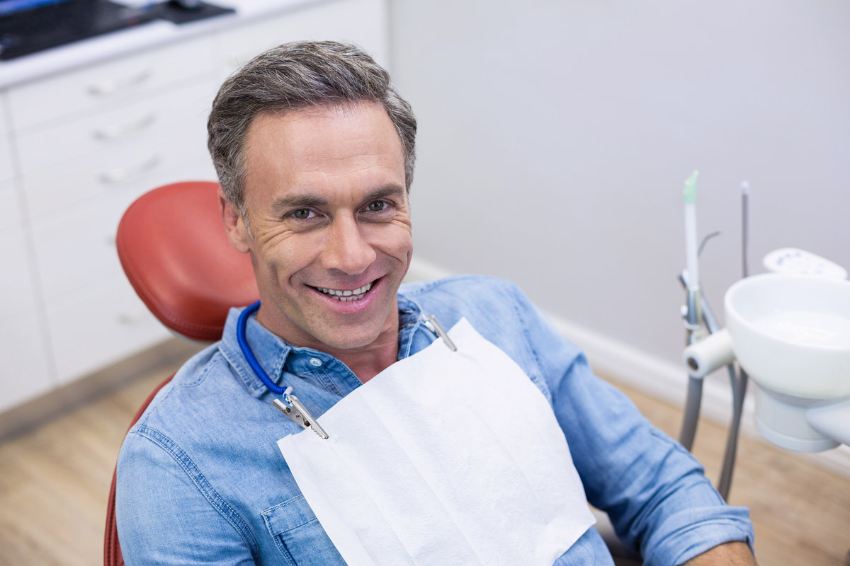 Smiling male patient sitting on dentist chair