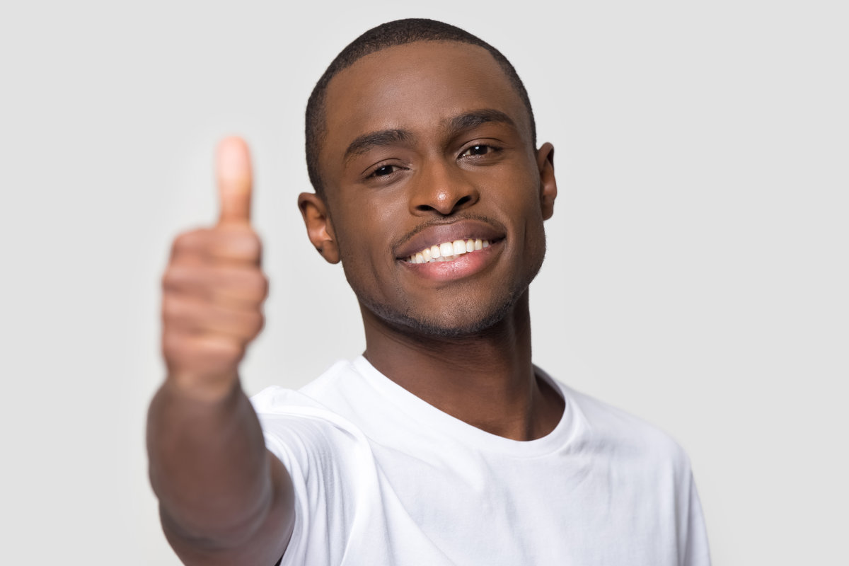 Close up face of happy African American man showing thumbs up, head shot portrait satisfied male with healthy white smile looking at camera, client recommend service, isolated on studio background