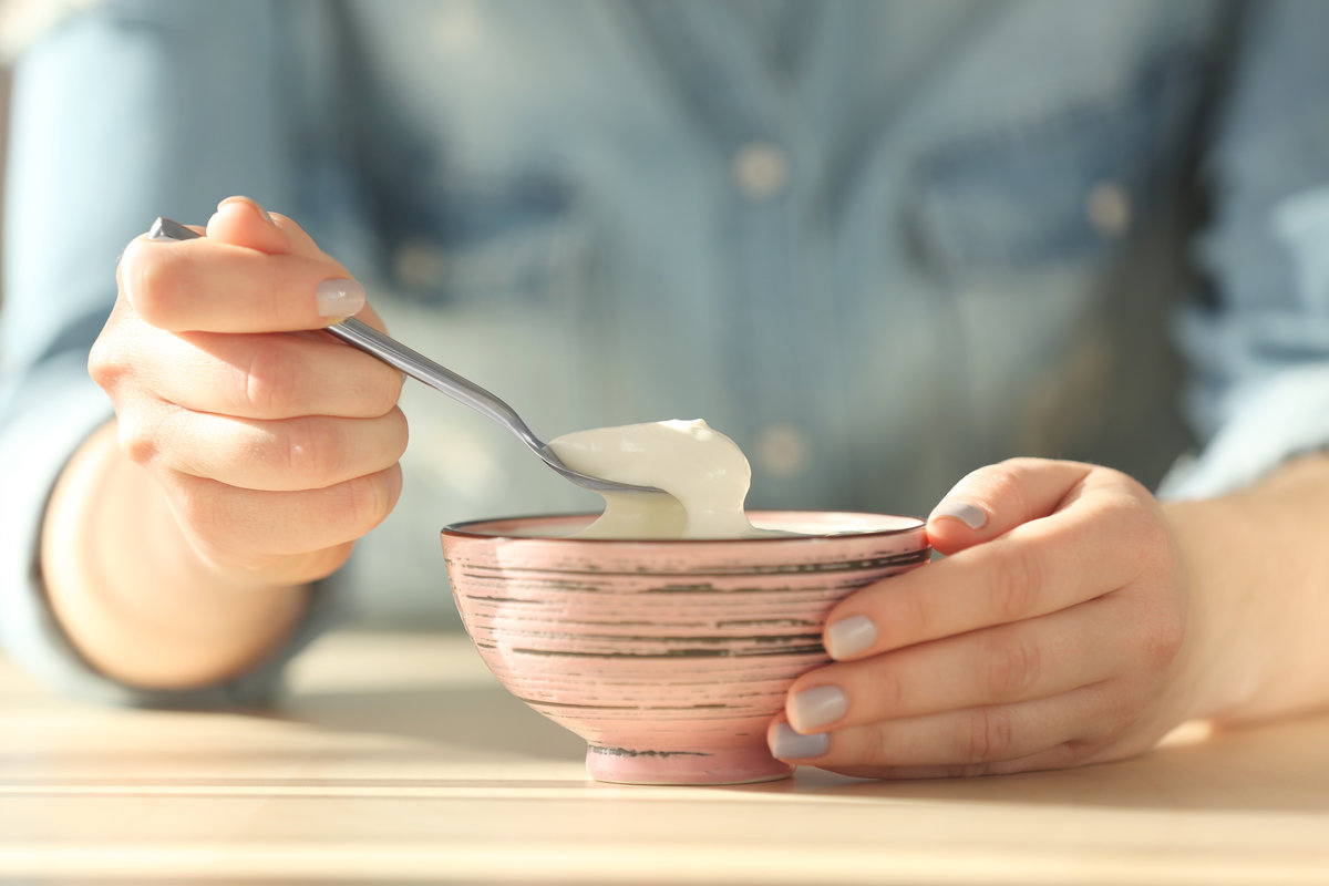 Bowl with yogurt and spoon in female hands